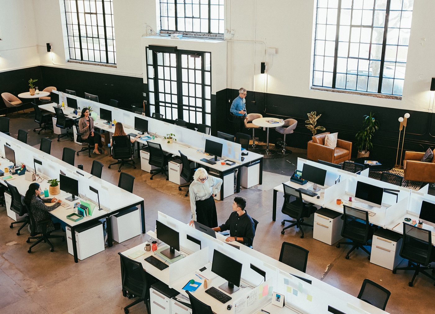Overhead view of an open-plan office with people working at rows of desks