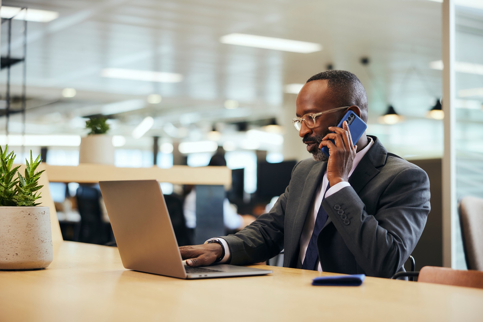 A finance leader on a call while reviewing figures on a laptop in an open-plan office